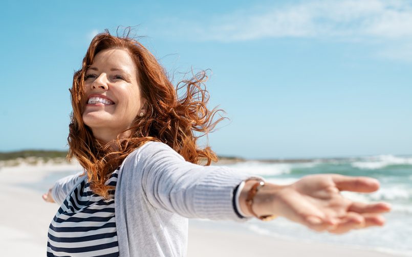 woman red hair frechles smiling on beach