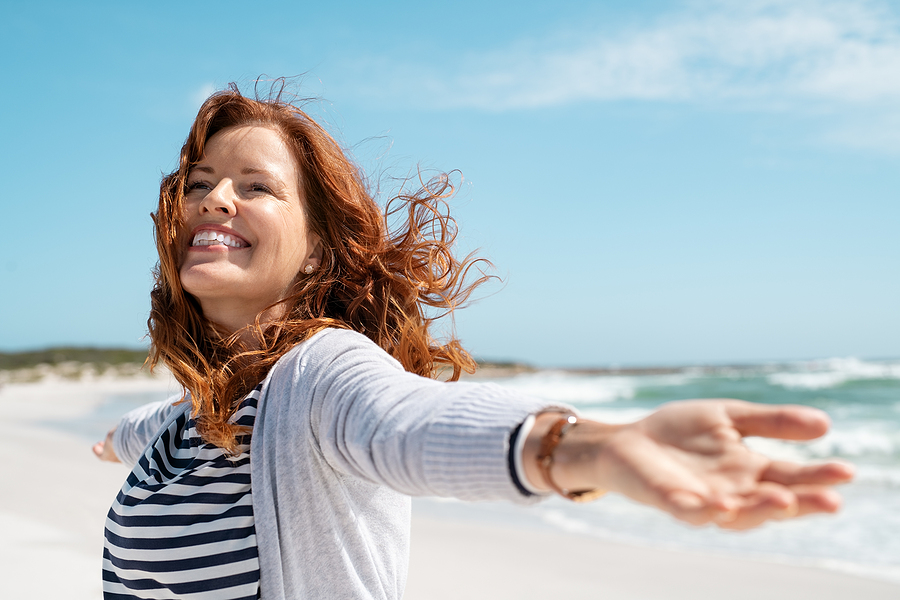 woman red hair frechles smiling on beach