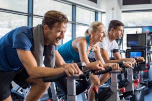 men and woman riding bikes in gym