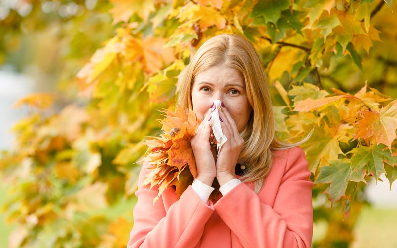 blonde woman kleenex in front of fall tree