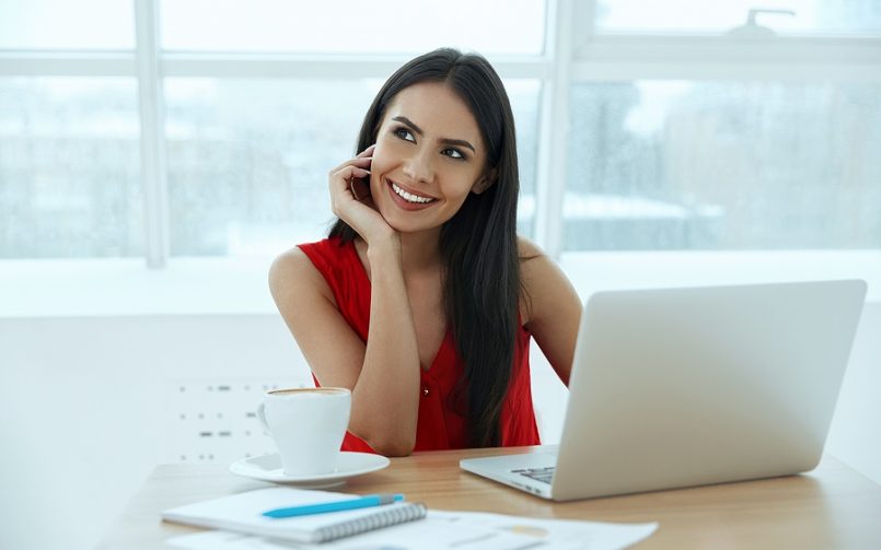 dark hair woman in red top thinking at desk